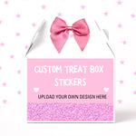 A white treat box with a pink satin bow on top, featuring a pink front label that reads 'CUSTOM TREAT BOX STICKERS' and 'UPLOAD YOUR OWN DESIGN HERE.